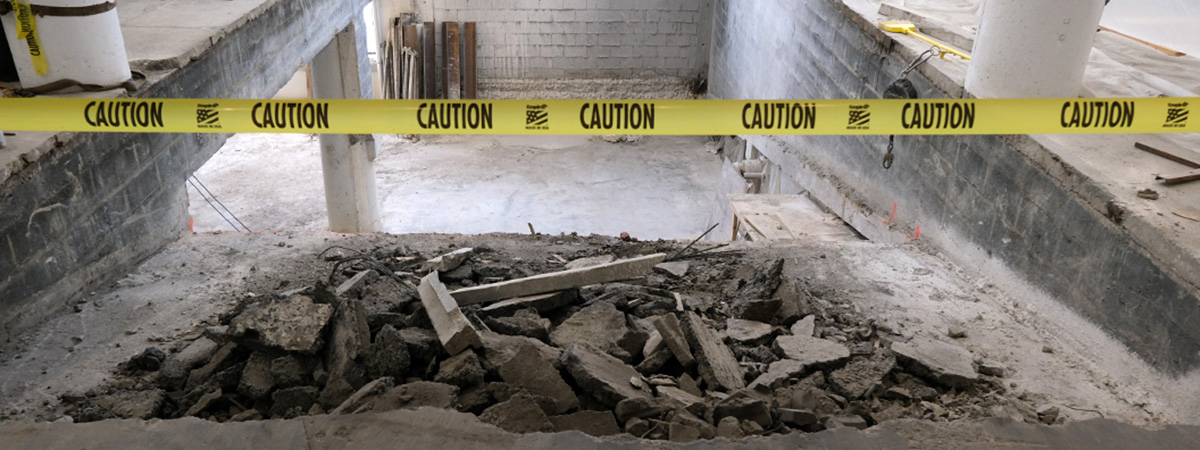 A rubble-strewn construction zone with yellow caution tape.