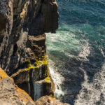 A photo of a craggy cliff over ocean waves in Ballyvaughan, Ireland.