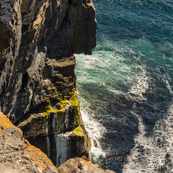 Ireland25_Parker-Deutsch_01 A photo of a craggy cliff over ocean waves in Ballyvaughan, Ireland.