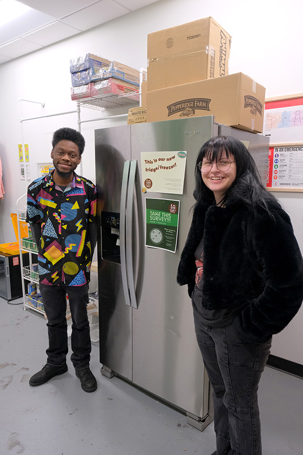 MIAD students Fig and Simon stand in front of the Peoples Pantry fridge.