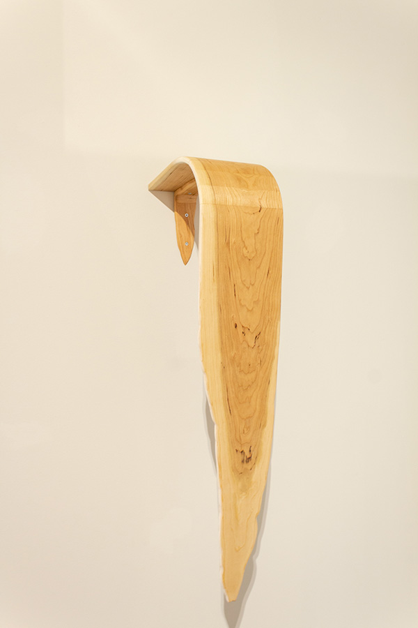 A wooden sculpture hanging down a wall like a waterfall.