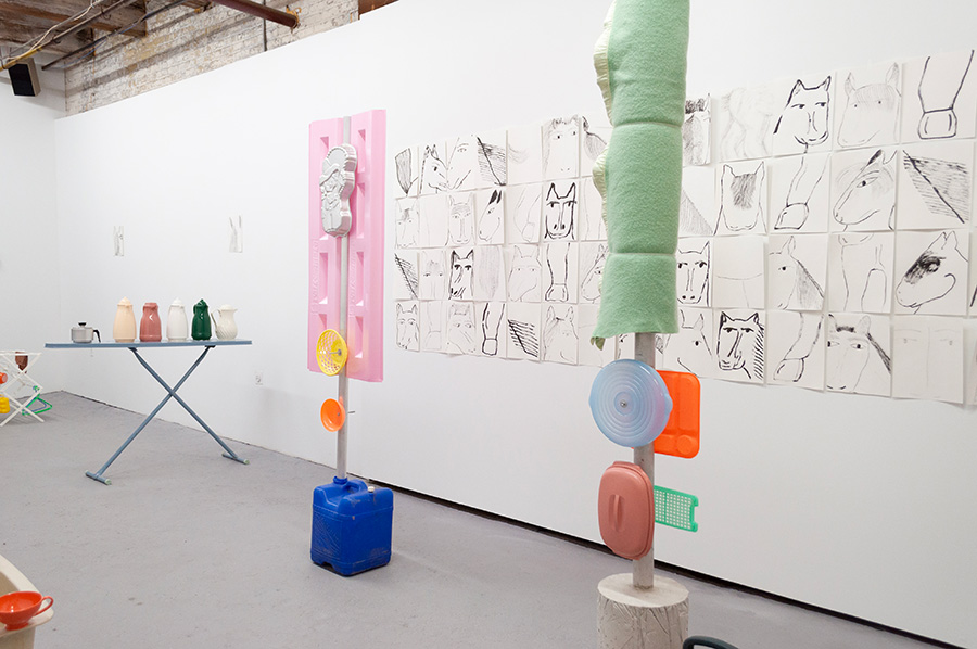 A sculptural installation with found objects and line drawings of horses on paper on the wall