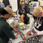 A group of students uses paper cutters.