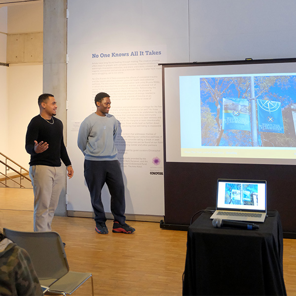 Two students smile and present a powerpoint at the Haggerty Museum of Art