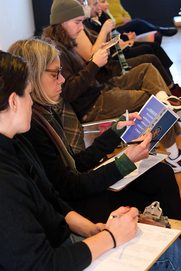 A group of audience members reads hypothetical exhibition materials.