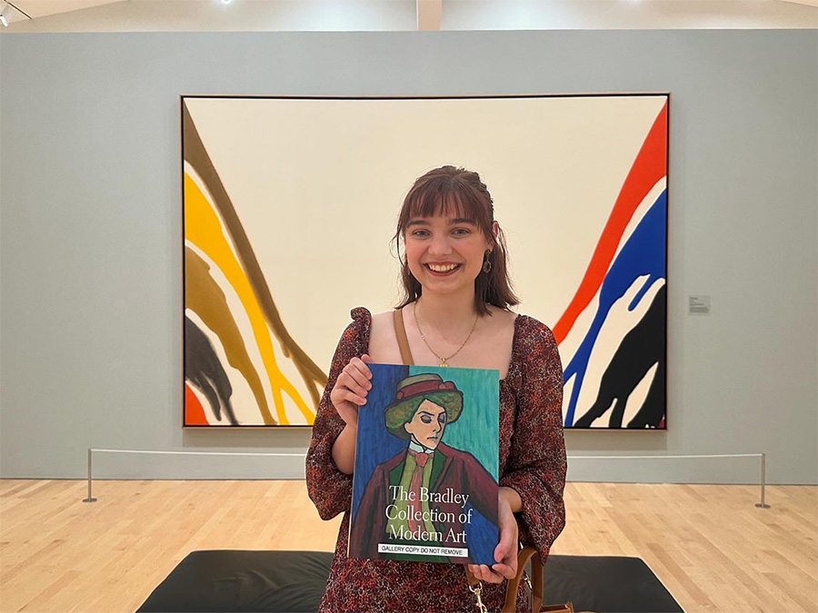 Nikki Ranney holds "The Bradley Collection of Modern Art" in front of a large painting.
