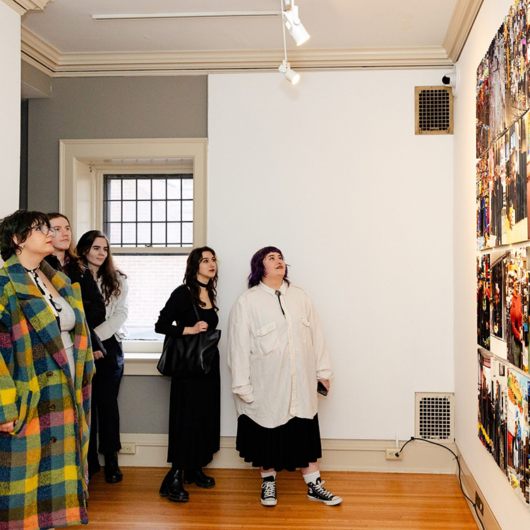 A group of people looking at Ashley Osorio's printed photographs hanging on a wall.