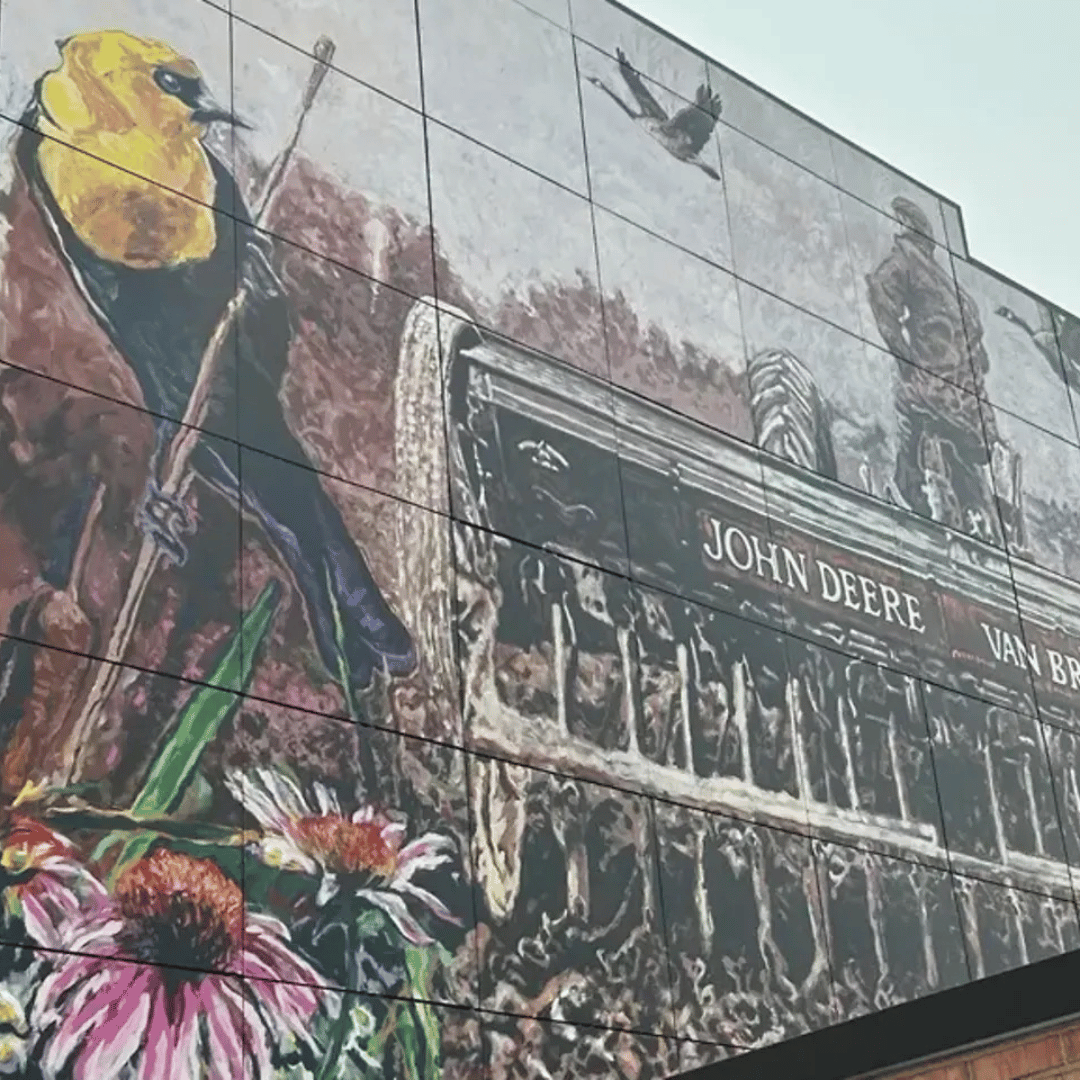 Mural panel featuring a yellow bird, wildflowers, and a historic John Deere Van Brunt agricultural seed drill.