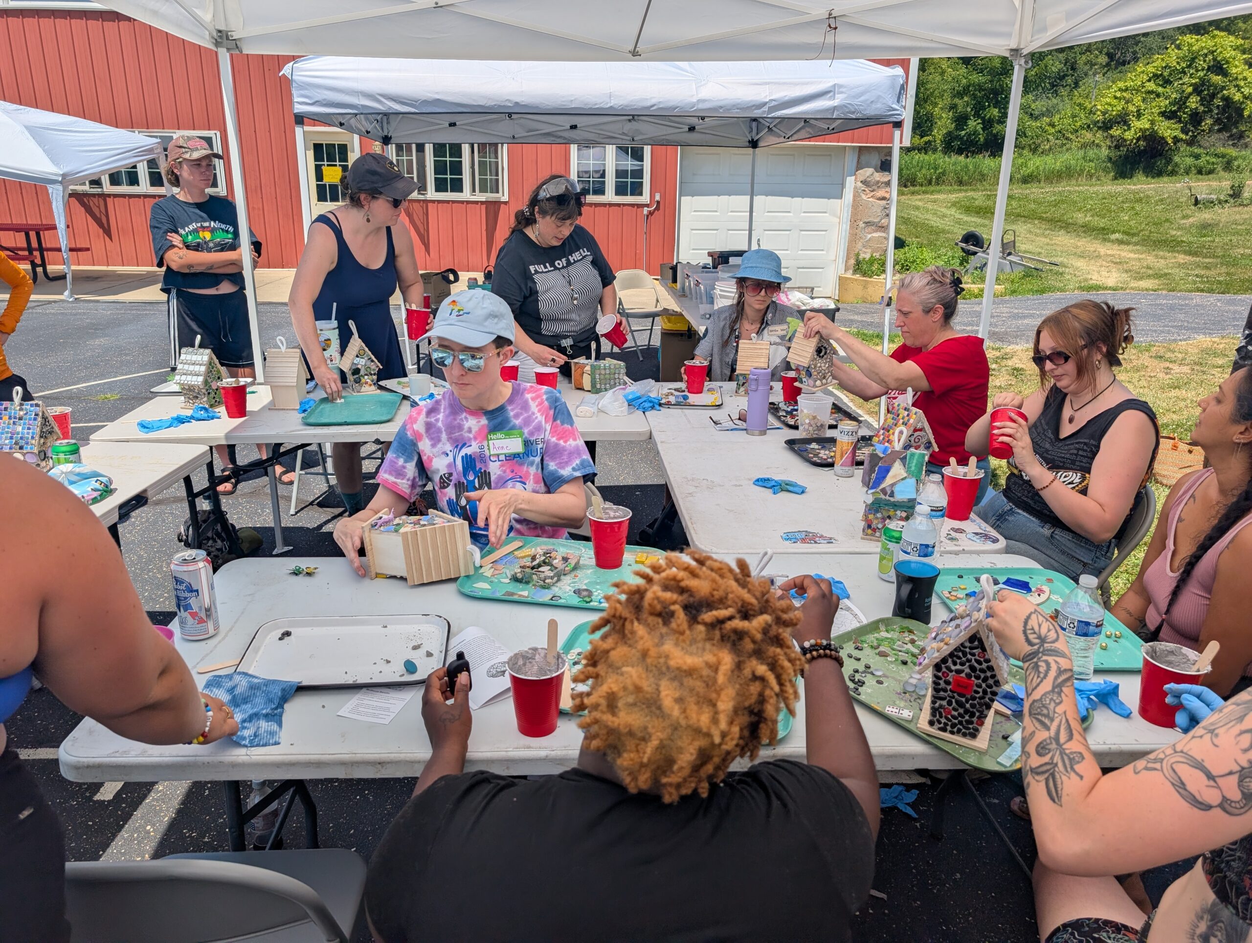 A group of people sitting at multiple tables making art and crafts.